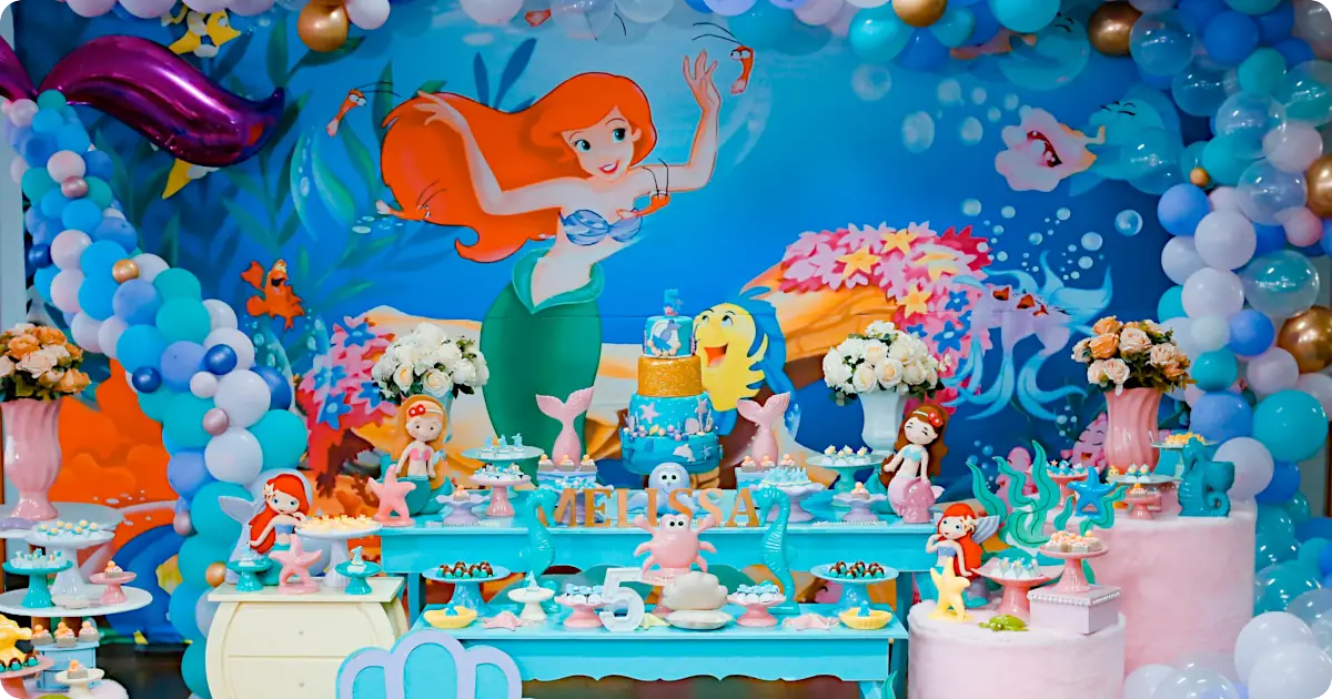 Amazing mermaid party with little mermaid backdrop, balloons, and table with mermaid cake, snacks and decorations
