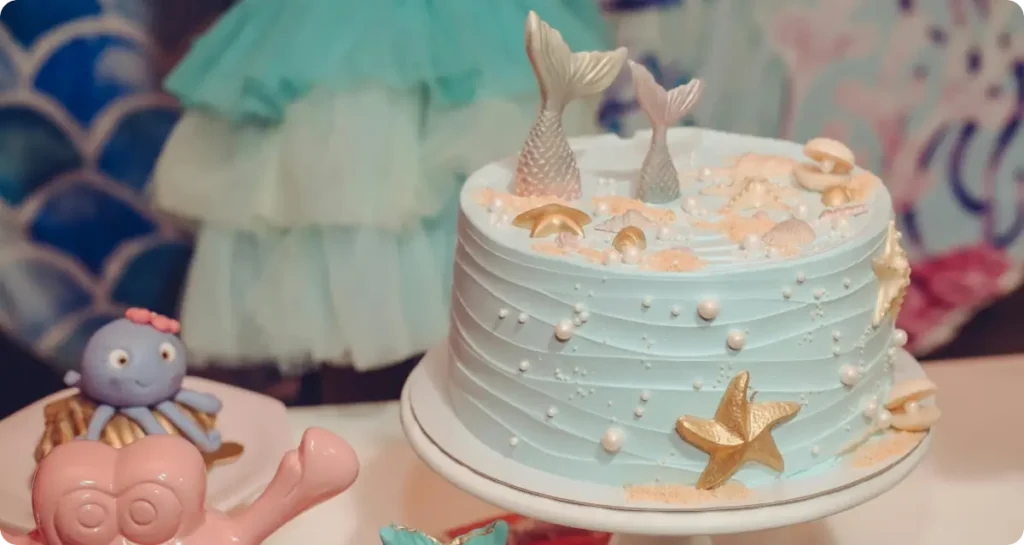 Mermaid theme birthday cake on table with party decorations
